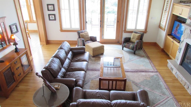 living room featuring light wood-style floors, baseboards, and a glass covered fireplace