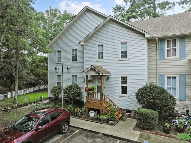 view of front facade with uncovered parking, crawl space, roof with shingles, and fence