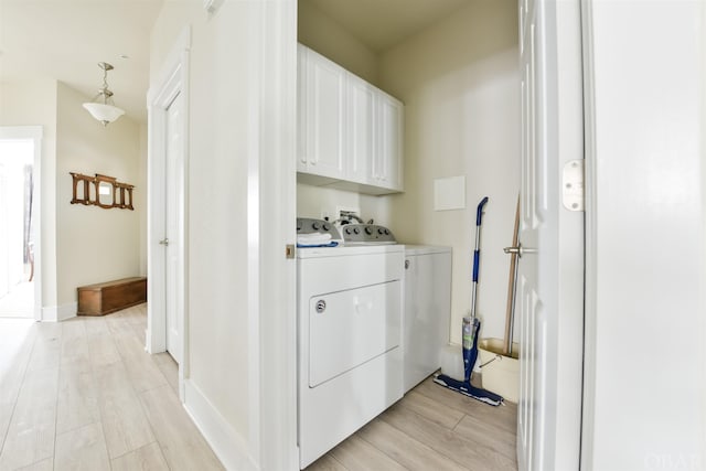 laundry area with wood finish floors, independent washer and dryer, cabinet space, and baseboards