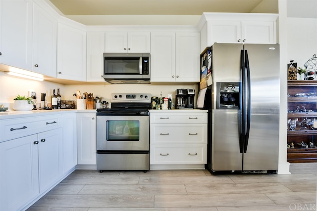 kitchen with light countertops, appliances with stainless steel finishes, wood tiled floor, and white cabinets