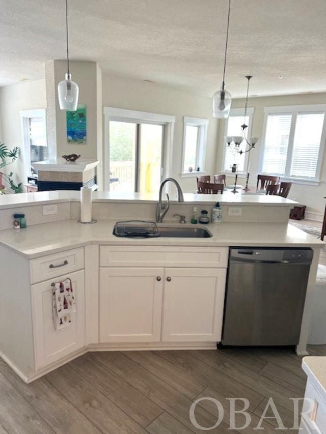 kitchen featuring a sink, white cabinetry, light countertops, dishwasher, and pendant lighting