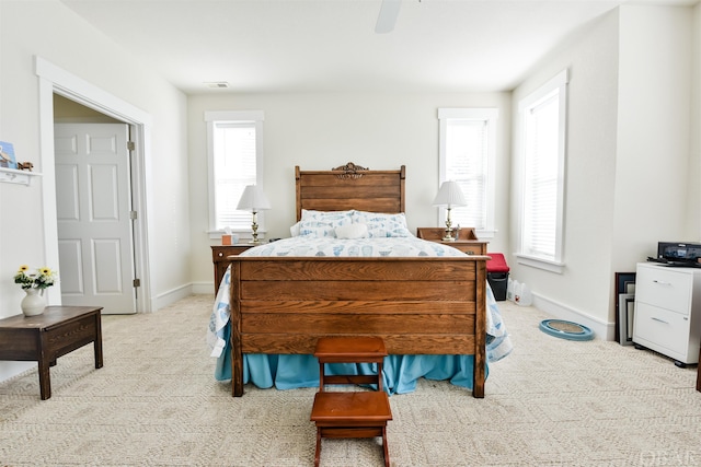 bedroom with a ceiling fan, light carpet, visible vents, and baseboards