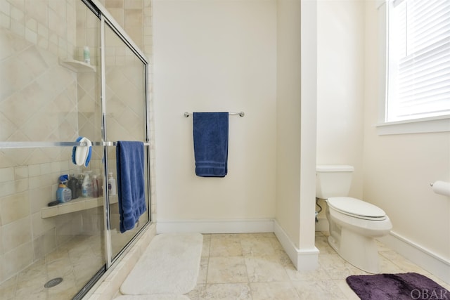 bathroom with a shower stall, toilet, and baseboards