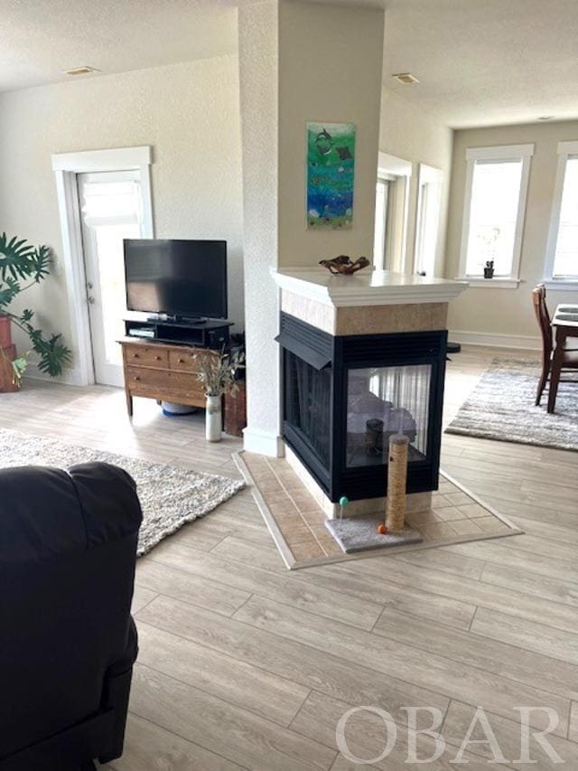 living area with baseboards, wood finished floors, and a tile fireplace