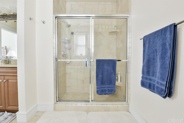 bathroom with a stall shower, baseboards, and vanity