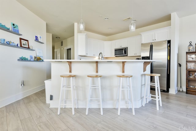 kitchen with decorative light fixtures, stainless steel appliances, light countertops, visible vents, and white cabinetry