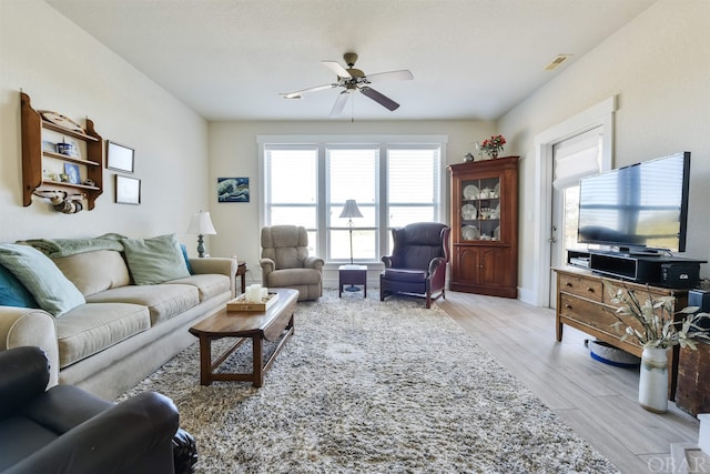 living room featuring a ceiling fan, visible vents, and light wood finished floors