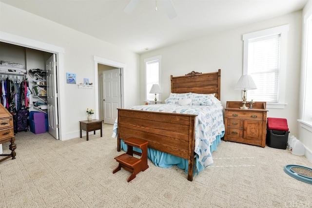 bedroom featuring baseboards, a ceiling fan, light colored carpet, a walk in closet, and a closet