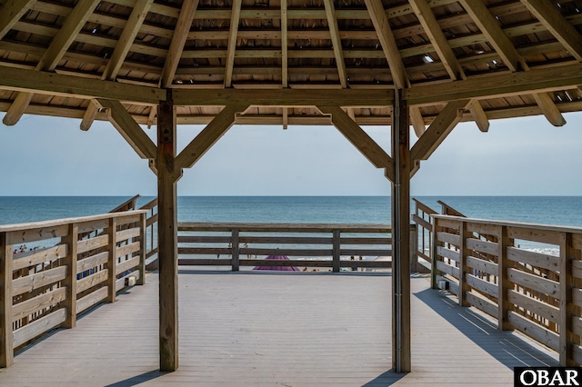 view of property's community with a gazebo, a deck with water view, and a view of the beach