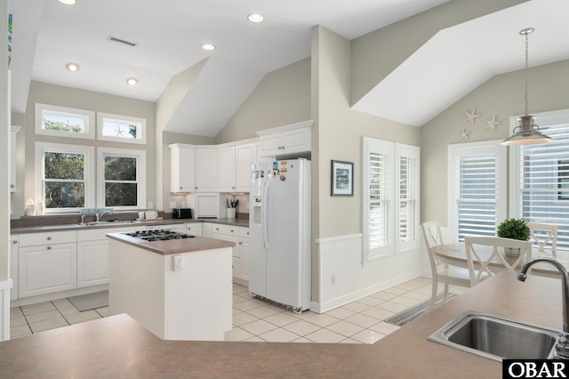 kitchen featuring white fridge with ice dispenser, a center island, white cabinetry, and a sink