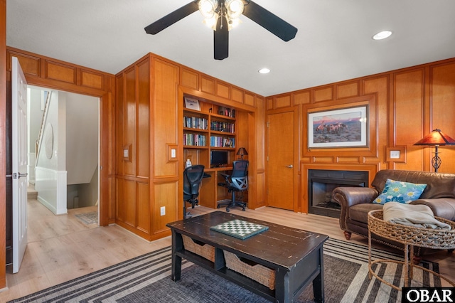 living area with wood walls, light wood-style flooring, and a decorative wall