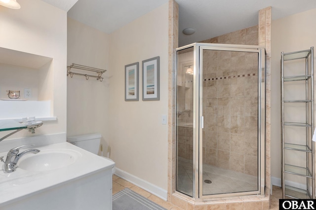 bathroom featuring a stall shower, vanity, baseboards, and tile patterned floors