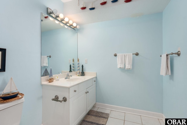 half bathroom featuring tile patterned flooring, baseboards, vanity, and toilet