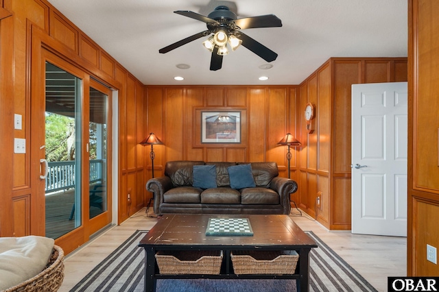 living room featuring light wood-type flooring, a decorative wall, and a ceiling fan