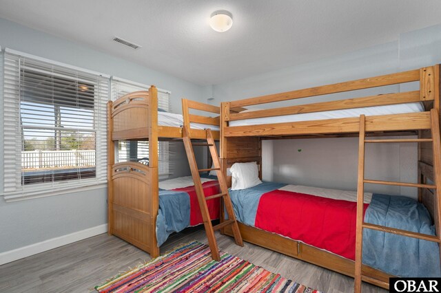 bedroom featuring baseboards, visible vents, and wood finished floors