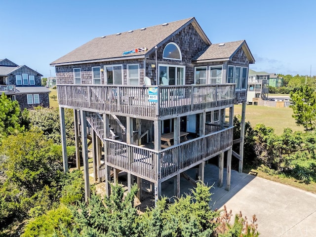 rear view of house featuring a shingled roof and a deck