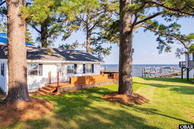 rear view of property featuring a deck with water view and a yard