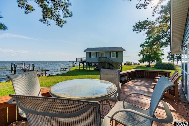 wooden terrace featuring a dock, outdoor dining area, a water view, and boat lift