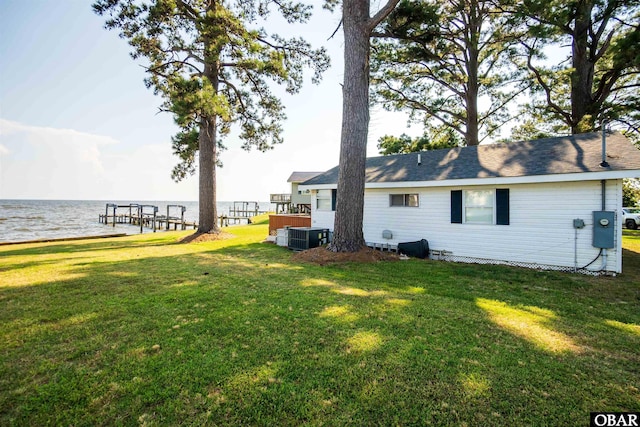 rear view of house featuring cooling unit, a water view, and a lawn