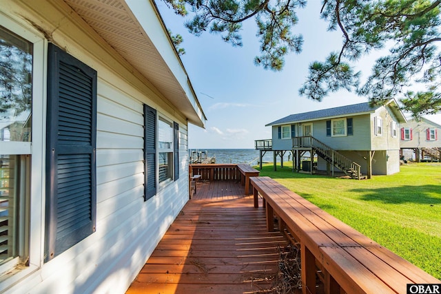 wooden terrace featuring a water view and a lawn