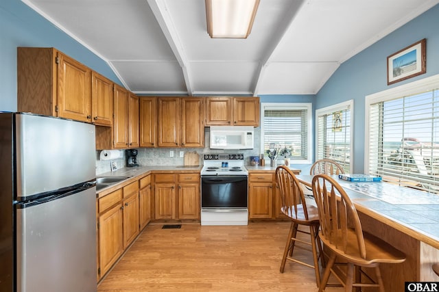 kitchen featuring white microwave, range with electric cooktop, vaulted ceiling, and freestanding refrigerator