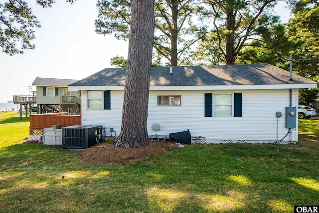 rear view of property with cooling unit and a yard