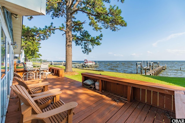 deck with a water view, a boat dock, boat lift, and a lawn