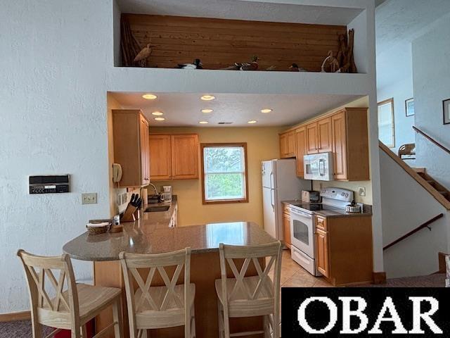 114 Poteskeet Dr Lot 66, Kitty Hawk, NC 27949 - kitchen featuring white appliances, a peninsula, a kitchen breakfast bar, a textured wall, and a sink