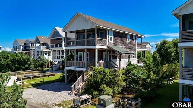 74 Lake Dr, Ocracoke, NC 27960 - back of property with stairway, a vegetable garden, a balcony, and a sunroom