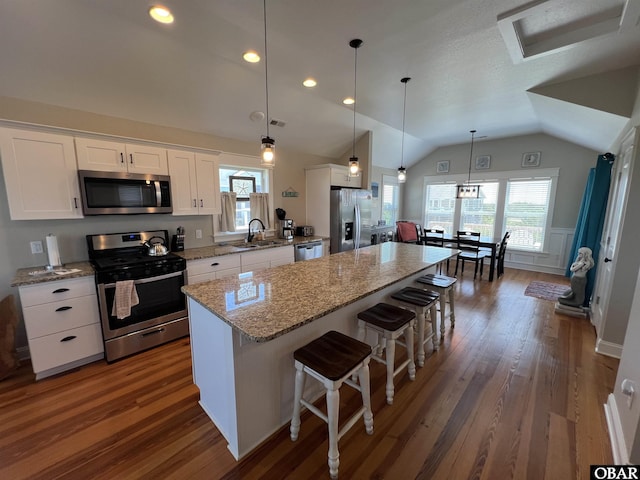 74 Lake Dr, Ocracoke, NC 27960 - kitchen with stainless steel appliances, white cabinetry, a center island, a kitchen breakfast bar, and vaulted ceiling