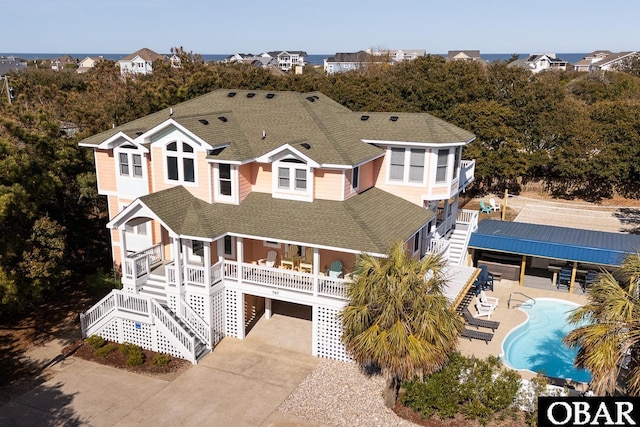 567 Ocean Trl Lot 140, Corolla, NC 27927 - view of front of house featuring stairway, a shingled roof, driveway, a carport, and an outdoor pool