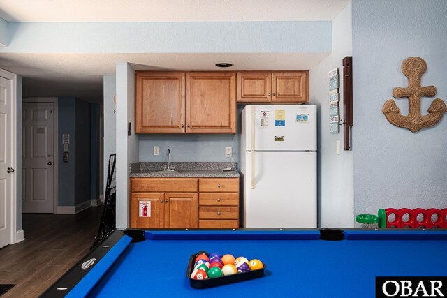 567 Ocean Trl Lot 140, Corolla, NC 27927 - kitchen with freestanding refrigerator, brown cabinetry, a sink, and dark wood finished floors