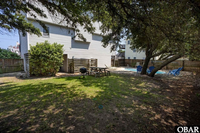 rear view of house featuring a fenced backyard, a fenced in pool, and a lawn