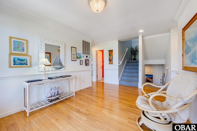 sitting room featuring wood-type flooring, crown molding, and stairway