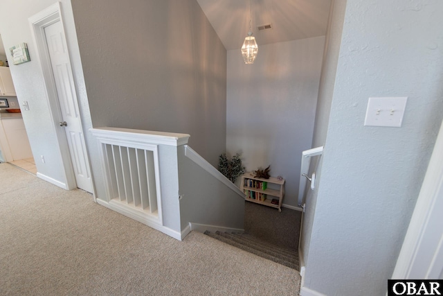 stairway featuring baseboards, visible vents, a textured wall, an inviting chandelier, and carpet floors