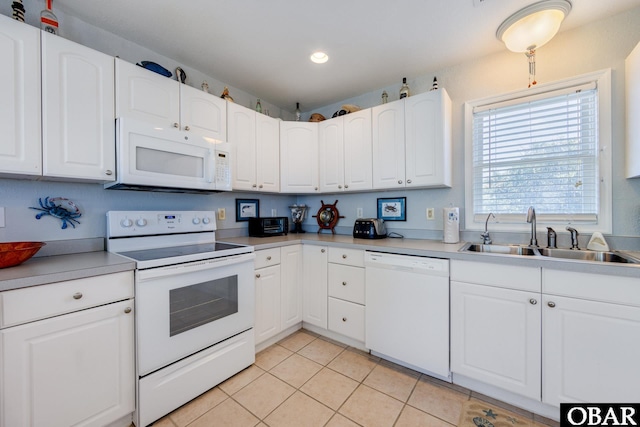 kitchen featuring white appliances, white cabinetry, a sink, and light tile patterned flooring