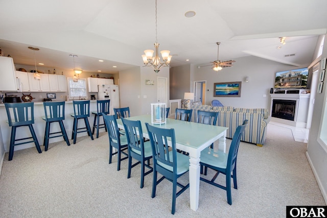 dining room with recessed lighting, a fireplace, vaulted ceiling, and light colored carpet