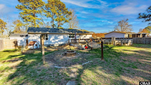 back of property with a yard, a fenced in pool, a fenced backyard, and an outdoor fire pit