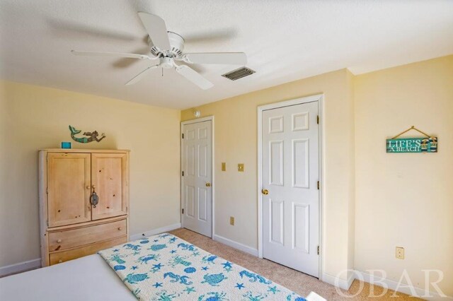 bedroom with baseboards, visible vents, a ceiling fan, and light colored carpet