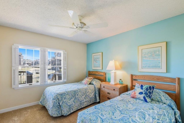 bedroom featuring a ceiling fan, a textured ceiling, baseboards, and carpet flooring