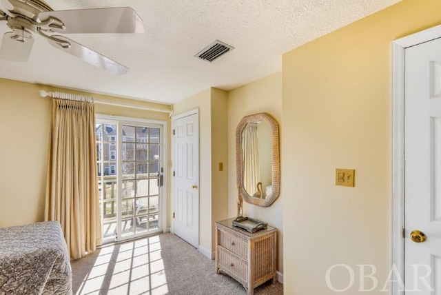 doorway to outside with visible vents, ceiling fan, light carpet, and a textured ceiling