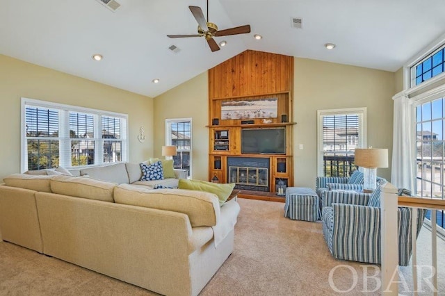 living area featuring a large fireplace, visible vents, high vaulted ceiling, and light colored carpet