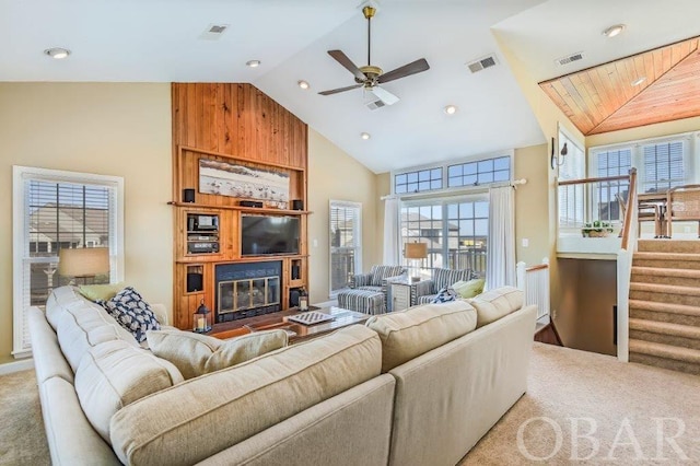 living area featuring high vaulted ceiling, a large fireplace, visible vents, and light carpet