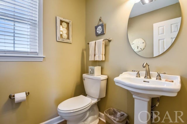 half bathroom with toilet, baseboards, and visible vents