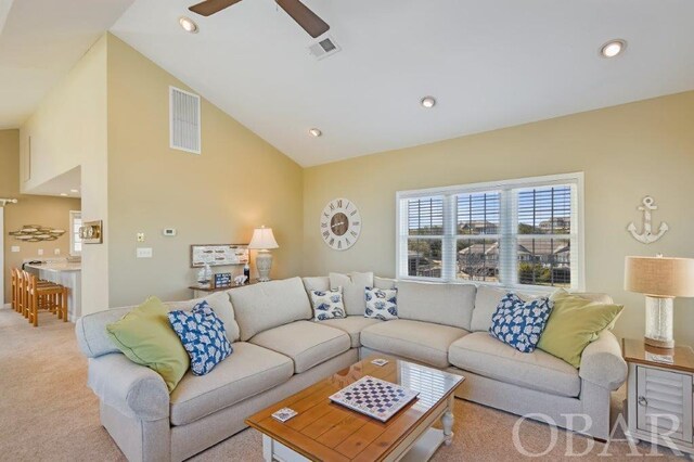 living room with high vaulted ceiling, recessed lighting, visible vents, and light colored carpet