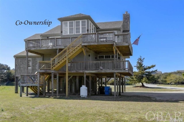 back of house featuring a lawn, a chimney, a wooden deck, and stairs