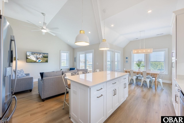 kitchen with stainless steel fridge, open floor plan, decorative light fixtures, light countertops, and white cabinetry