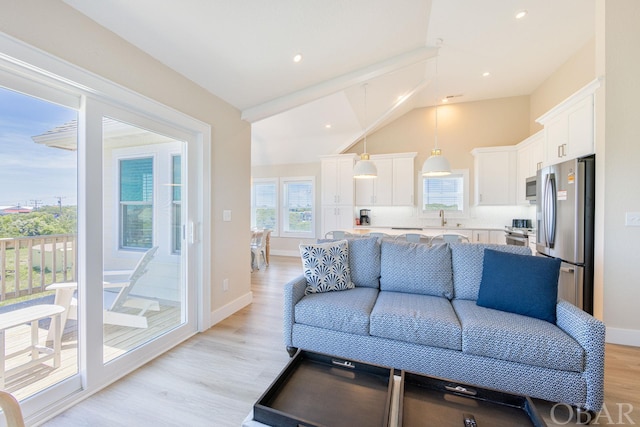 living area with recessed lighting, light wood-type flooring, a towering ceiling, and baseboards