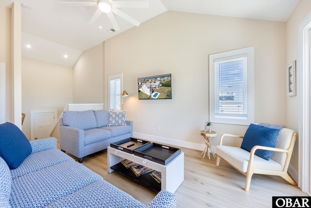 living room with light wood-type flooring, a healthy amount of sunlight, and vaulted ceiling