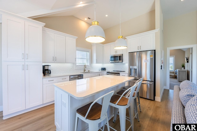 kitchen featuring a sink, white cabinetry, light countertops, appliances with stainless steel finishes, and decorative light fixtures